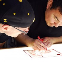 Ivan Lecaros (right), a master printmaker from Chile, puts the final touches on a drawing for a silkscreen print during his 2012 residency at Zygote Press.